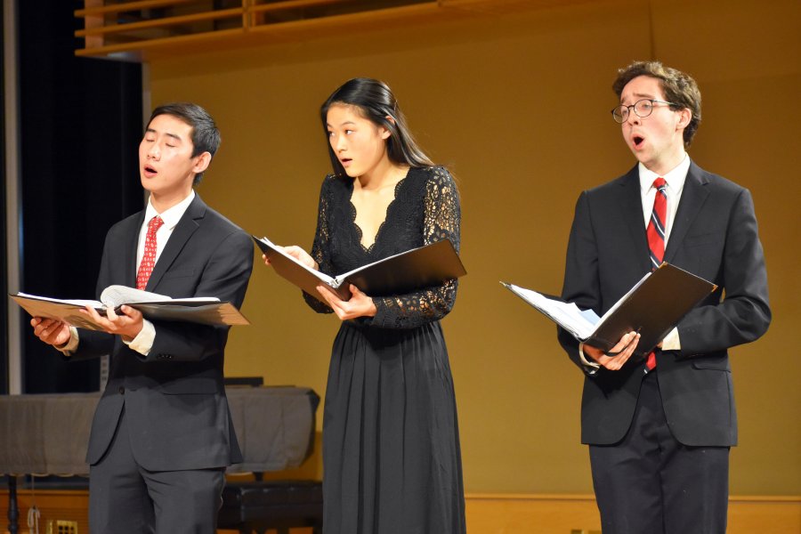 Three Exeter students singing during a performance.