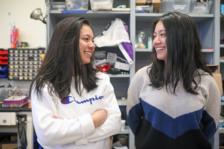 Anjali and Meili Gupta smile at each other standing in the Design Lab. 