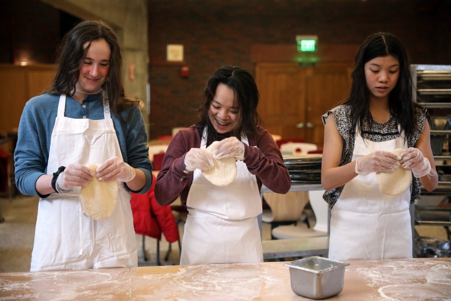 Three students working with pizza dough.