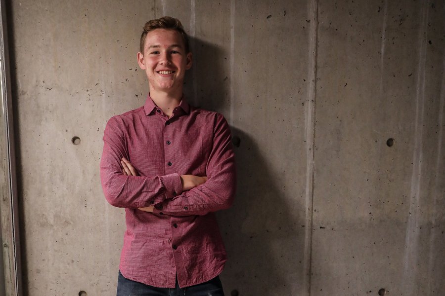 Billy Menken standing in front of a concrete wall. 