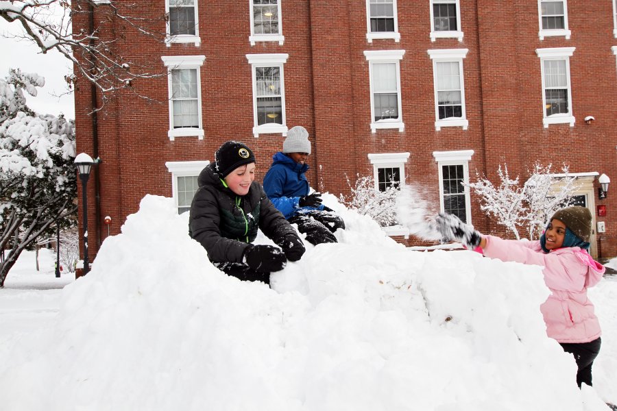 Kids play on a snowbank on Exeter's campus.