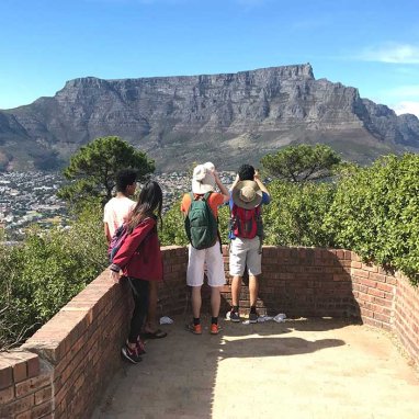 Three students looking out at a mountain range