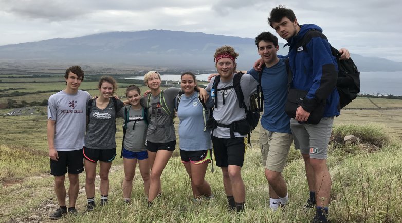 A group of Exeter students standing in front of the ocean in Maui